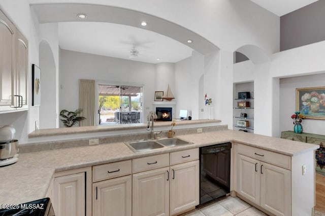 kitchen featuring a sink, open floor plan, black dishwasher, ceiling fan, and light countertops