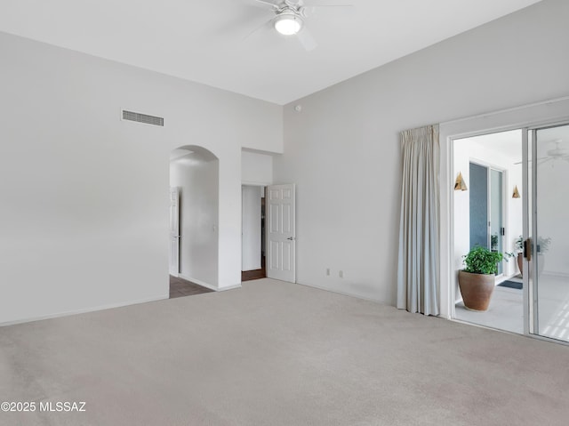 carpeted spare room featuring arched walkways, visible vents, and ceiling fan