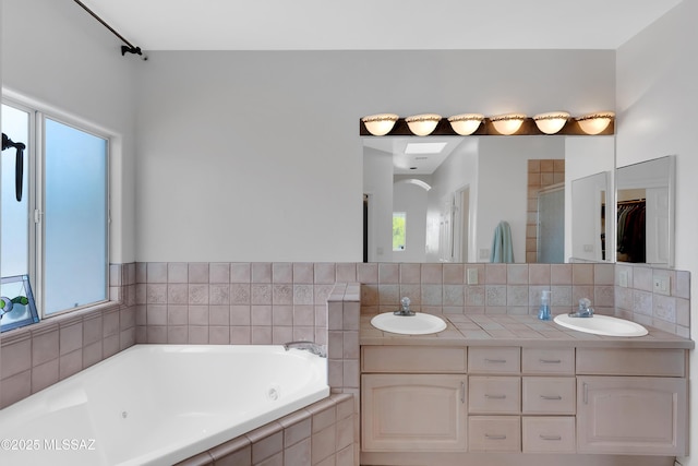 full bathroom with plenty of natural light, a tub with jets, and a sink