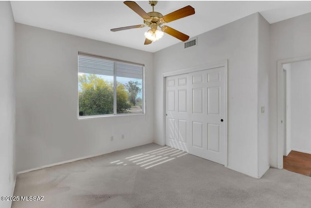 unfurnished bedroom featuring carpet floors, a ceiling fan, visible vents, and a closet