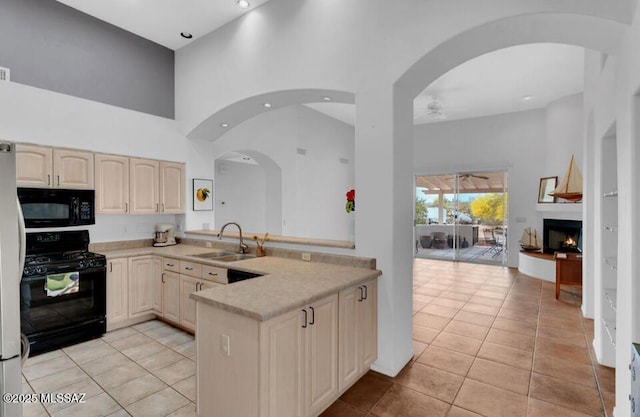 kitchen featuring a ceiling fan, a sink, black appliances, light tile patterned floors, and a peninsula