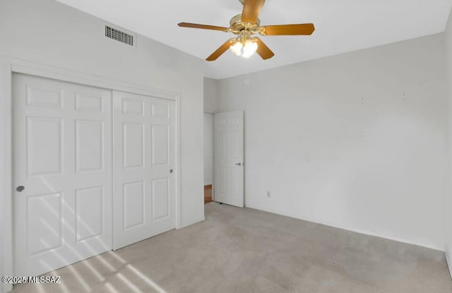 unfurnished bedroom featuring a ceiling fan, carpet flooring, visible vents, and a closet