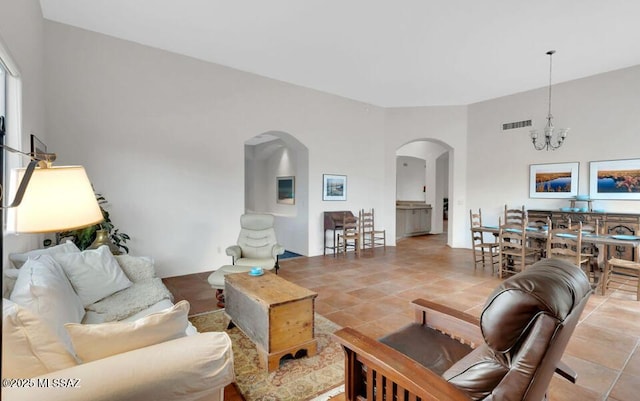 living area with arched walkways, visible vents, and an inviting chandelier