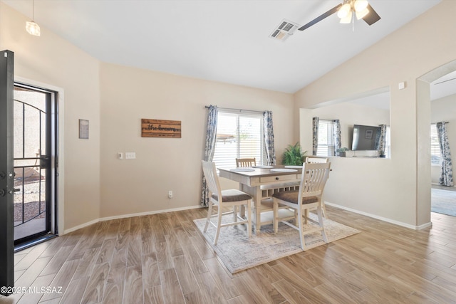 dining space featuring ceiling fan, vaulted ceiling, light wood-style floors, and visible vents