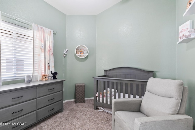 bedroom featuring a nursery area, baseboards, and light colored carpet