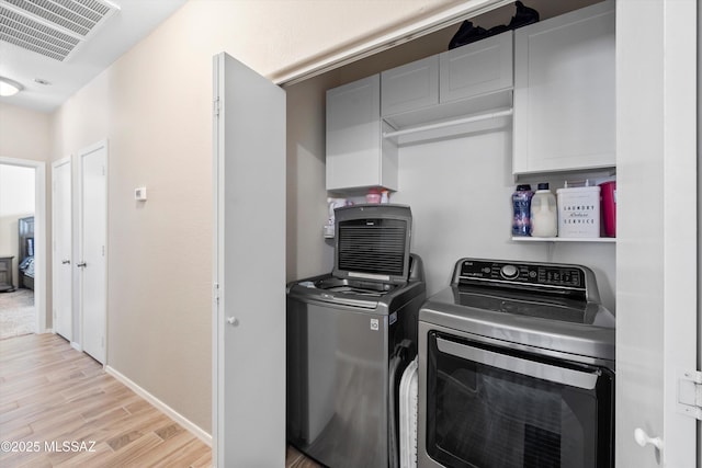 washroom featuring washer and clothes dryer, baseboards, visible vents, light wood-style floors, and laundry area
