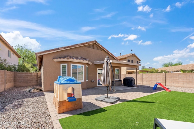 back of house featuring a patio area, a fenced backyard, a yard, and stucco siding