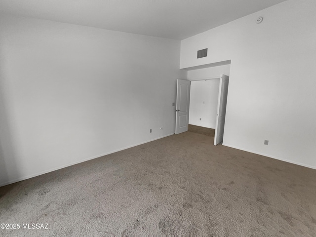carpeted empty room featuring baseboards, vaulted ceiling, and visible vents