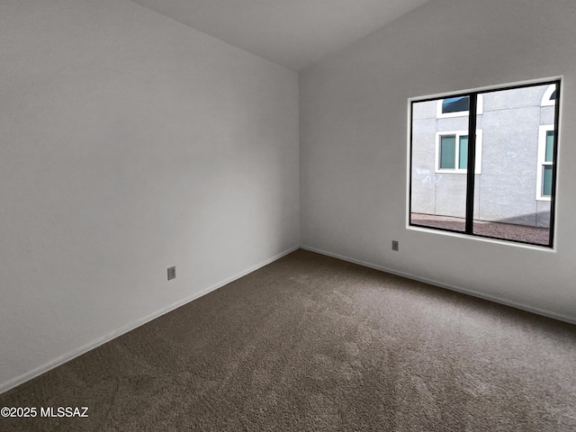carpeted spare room with baseboards and lofted ceiling