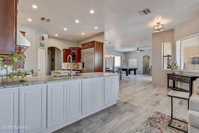 kitchen with arched walkways, stainless steel built in refrigerator, and visible vents