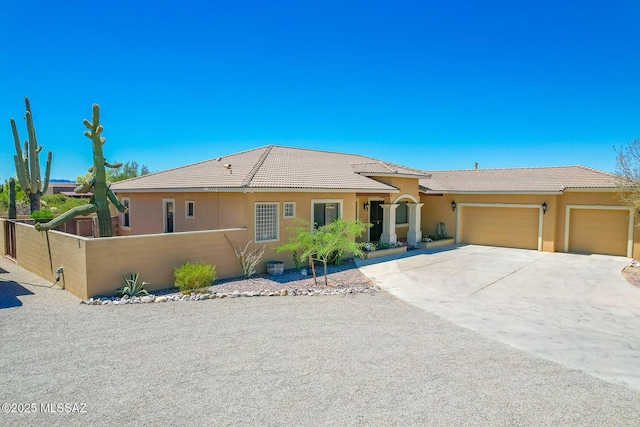 ranch-style house featuring an attached garage, fence, driveway, and stucco siding