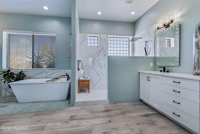 full bathroom featuring a marble finish shower, a soaking tub, vanity, and recessed lighting