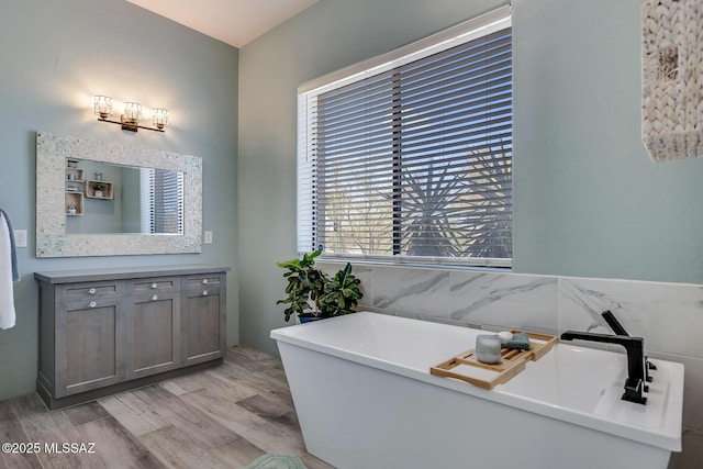 bathroom with vanity, a soaking tub, and wood finished floors