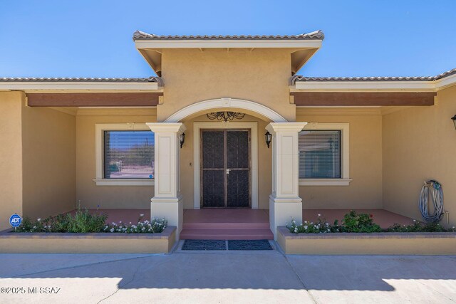 property entrance with a tile roof and stucco siding