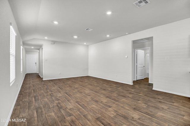 unfurnished room featuring dark wood-type flooring, visible vents, and baseboards