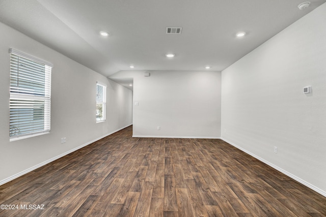 empty room featuring dark wood-type flooring, visible vents, baseboards, and recessed lighting