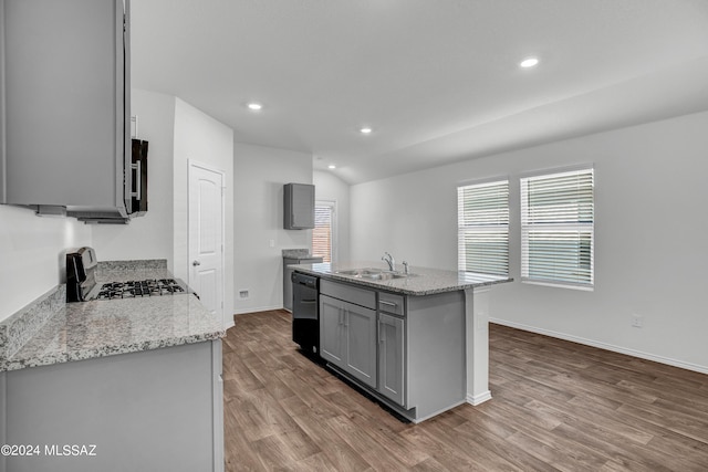 kitchen featuring gas range oven, gray cabinetry, dishwasher, a sink, and wood finished floors