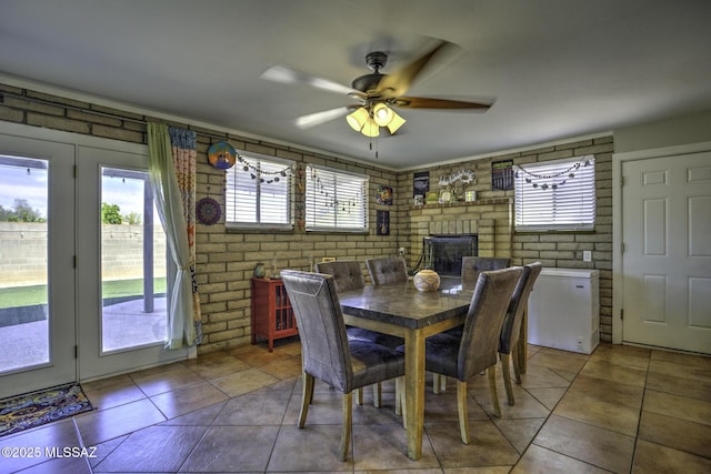 7217 E Fayette St, Tucson, AZ 85730 - dining room featuring ceiling fan, tile patterned floors, brick wall, and a brick fireplace