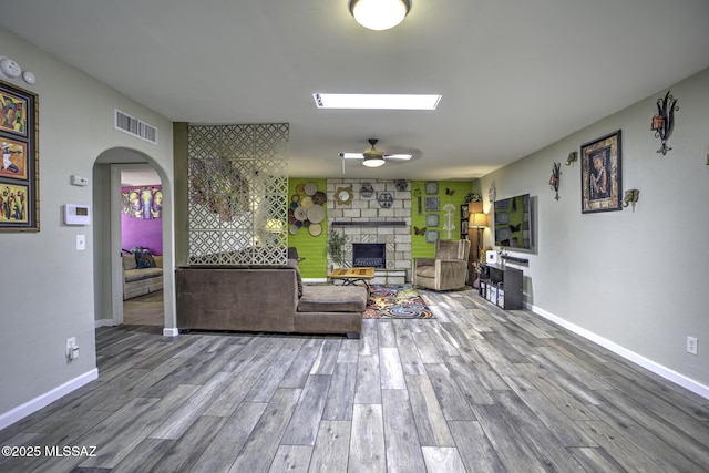 7217 E Fayette St, Tucson, AZ 85730 - living room featuring a stone fireplace, ceiling fan, wood finished floors, and arched walkways