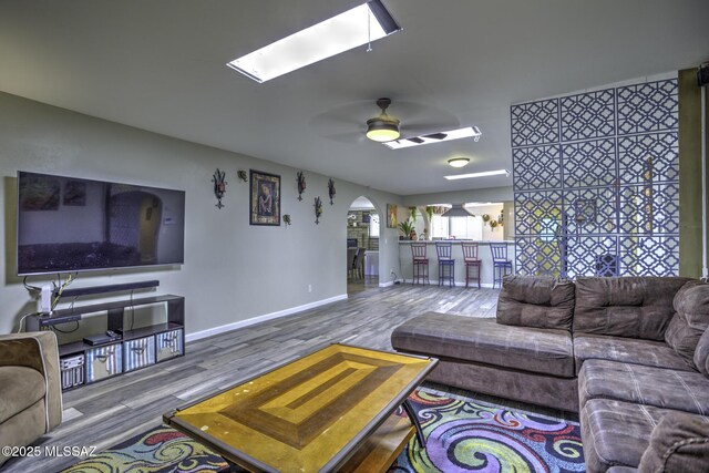 7217 E Fayette St, Tucson, AZ 85730 - living room featuring wood finished floors, a skylight, arched walkways, a ceiling fan, and baseboards
