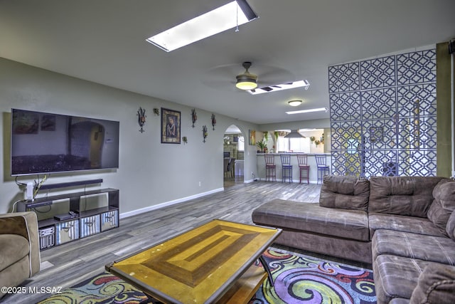7217 E Fayette St, Tucson, AZ 85730 - living room featuring wood finished floors, a skylight, ceiling fan, arched walkways, and baseboards