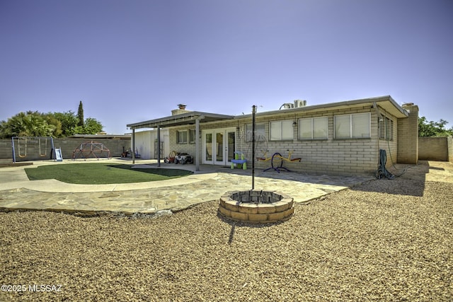 7217 E Fayette St, Tucson, AZ 85730 - back of property with french doors, an outdoor fire pit, a chimney, a fenced backyard, and a patio area