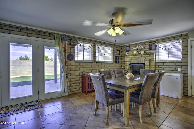 7217 E Fayette St, Tucson, AZ 85730 - dining space featuring a ceiling fan, brick wall, tile patterned floors, and a fireplace