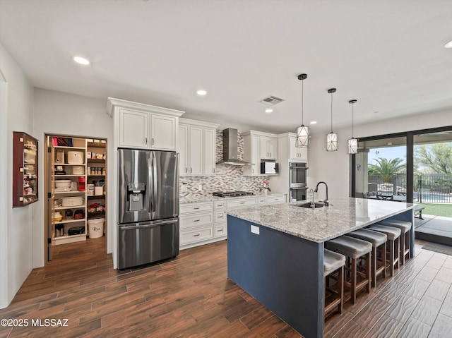 kitchen with wall chimney exhaust hood, white cabinetry, visible vents, stainless steel appliances, and dark wood-style floors