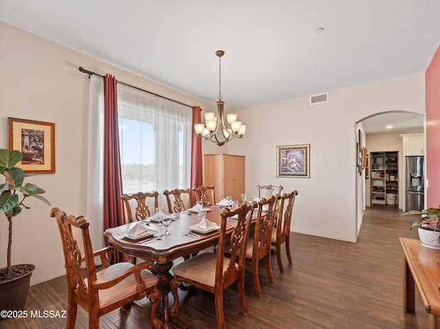 dining area with a chandelier, arched walkways, dark wood-style floors, and visible vents