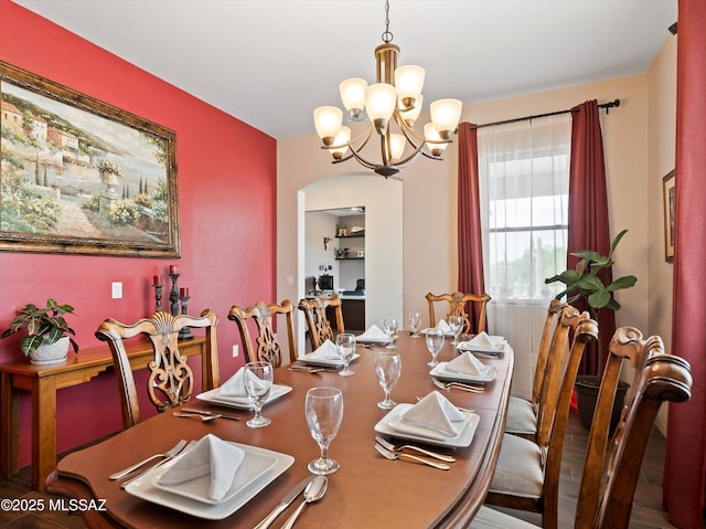 dining area with arched walkways and a notable chandelier