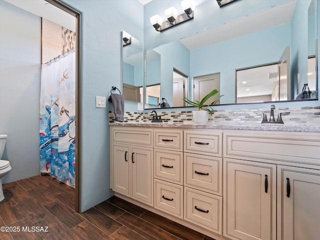 bathroom with backsplash, a sink, toilet, and wood finished floors