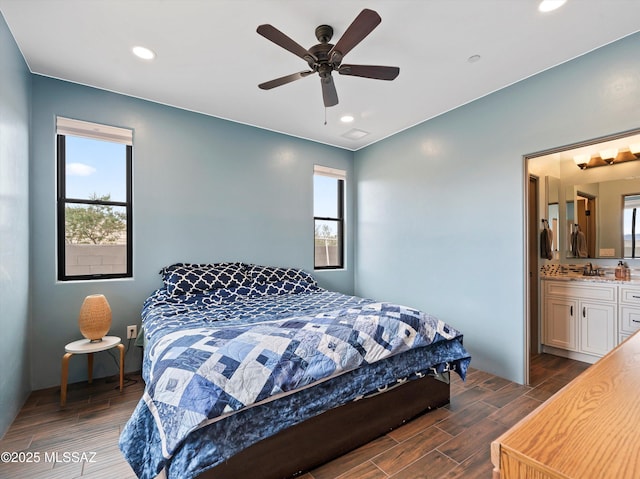 bedroom with recessed lighting, dark wood-type flooring, a sink, and ensuite bath
