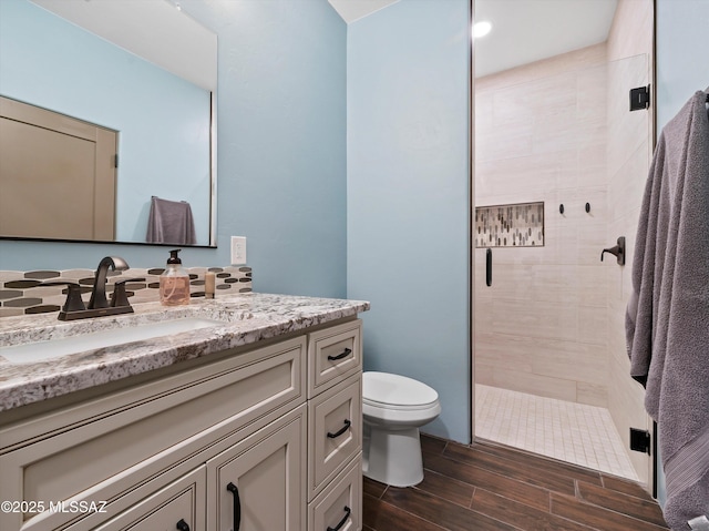 bathroom featuring toilet, a stall shower, vanity, and wood tiled floor