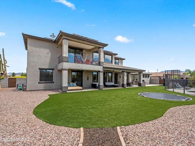rear view of property featuring a yard, stucco siding, a patio area, fence, and a balcony
