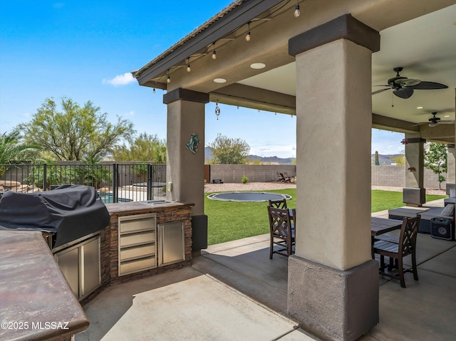 view of patio / terrace with ceiling fan, exterior kitchen, a fenced backyard, outdoor dining space, and grilling area