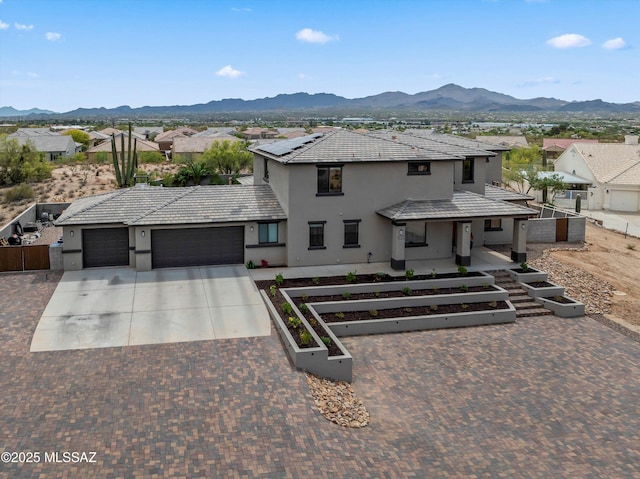 view of front of home with a garage, stucco siding, concrete driveway, a mountain view, and a residential view