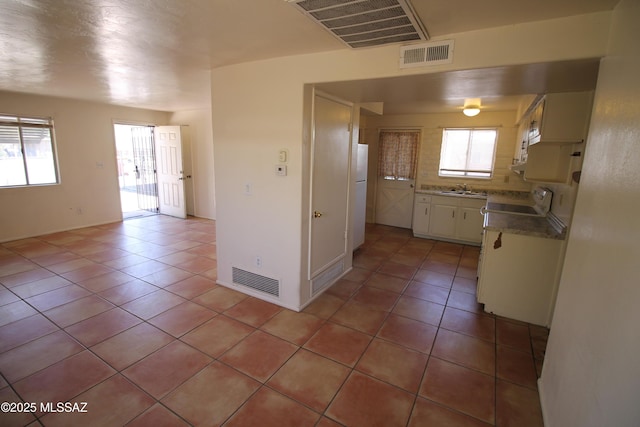 2665 N Leah Pl, Tucson, AZ 85705 - kitchen featuring a sink, light tile patterned flooring, white appliances, white cabinets, and baseboards