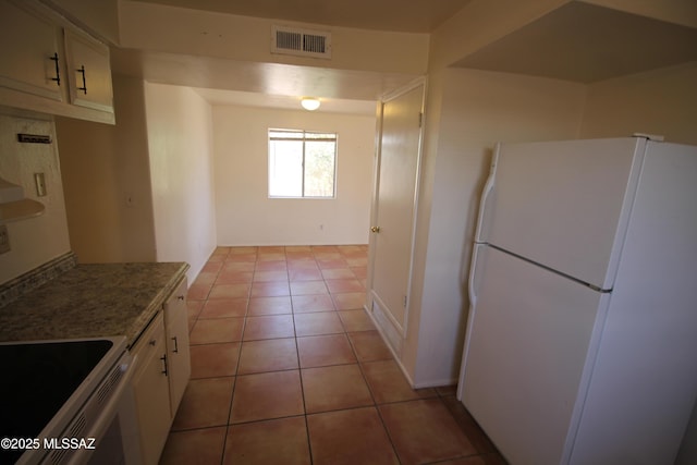 2665 N Leah Pl, Tucson, AZ 85705 - kitchen with freestanding refrigerator, white cabinets, light tile patterned floors, and electric stove