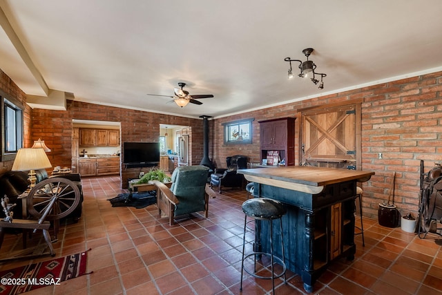 17300 S Camino Cartagena, Sahuarita, AZ 85629 - living room with a ceiling fan, brick wall, a wood stove, dark tile patterned flooring, and a wealth of natural light