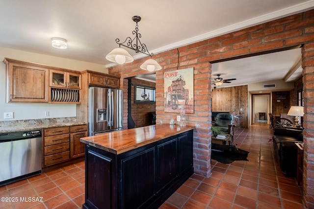 17300 S Camino Cartagena, Sahuarita, AZ 85629 - kitchen with brown cabinetry, pendant lighting, glass insert cabinets, dark tile patterned flooring, and appliances with stainless steel finishes