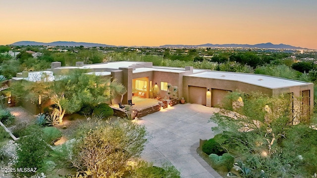 southwest-style home featuring an attached garage, concrete driveway, a mountain view, and stucco siding