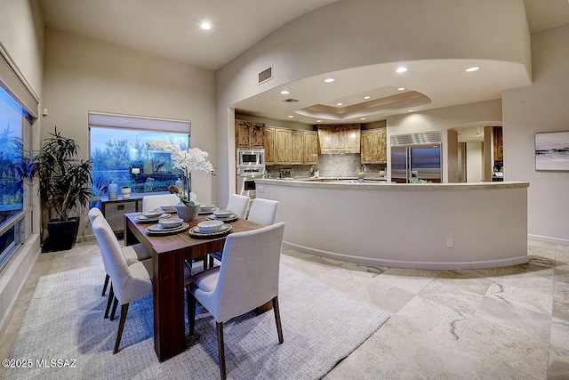 dining room with recessed lighting, a towering ceiling, visible vents, arched walkways, and baseboards