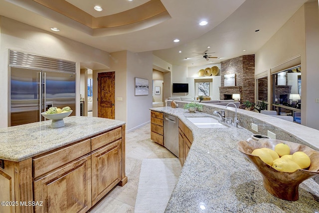 kitchen with stainless steel appliances, a sink, recessed lighting, ceiling fan, and light stone countertops