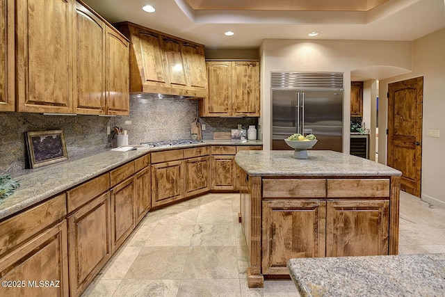 kitchen with a center island, decorative backsplash, stainless steel appliances, light stone countertops, and recessed lighting