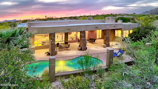 back of house with a chimney, fence, a patio, an outdoor pool, and stucco siding