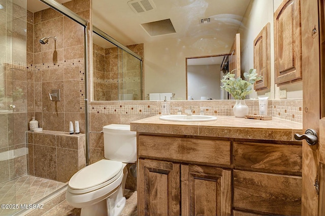 bathroom featuring a stall shower, vanity, tile walls, toilet, and visible vents