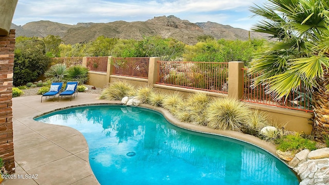 view of pool featuring fence, a patio area, a fenced in pool, and a mountain view