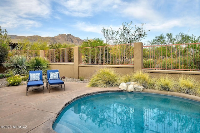 view of pool featuring a patio area, a fenced backyard, a fenced in pool, and a mountain view