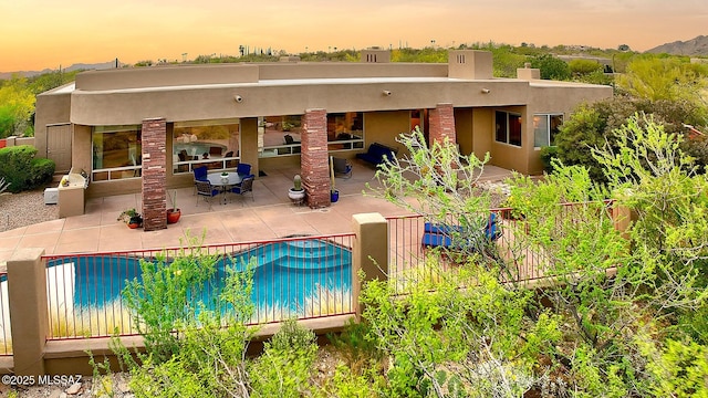 back of house with a patio area, a fenced in pool, and stucco siding