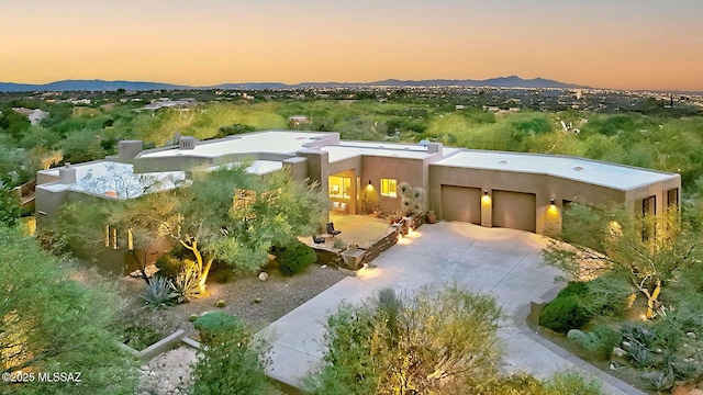 view of front facade featuring a garage, driveway, a mountain view, and stucco siding